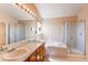 Well-lit bathroom with a double sink vanity, a large soaking tub, and glass shower door at 18995 E Bellisario Creek Pl, Parker, CO 80134