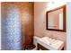 Stylish powder room featuring decorative wall tiles, a modern vanity, and an updated mirror at 18995 E Bellisario Creek Pl, Parker, CO 80134