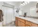 Bathroom with granite countertop, wood cabinets, and shower with white tile at 9375 Joyce Way, Arvada, CO 80007