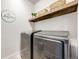 Modern laundry room with stainless steel washer and dryer, plus a wooden shelf at 9375 Joyce Way, Arvada, CO 80007