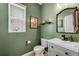 Stylish powder room with green walls, modern vanity, unique mirror, and elegant fixtures at 9375 Joyce Way, Arvada, CO 80007