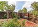 Fenced backyard featuring manicured garden beds, a decorative deer statue, and a wooden gate for added charm at 6687 Devinney Ct, Arvada, CO 80004