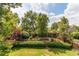 Lush backyard with a well-manicured lawn, mature trees, and charming landscaping features at 6687 Devinney Ct, Arvada, CO 80004