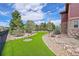 Beautiful backyard features a lush green synthetic lawn, a putting green, mature trees, and decorative rock landscaping at 7999 S Blackstone Pkwy, Aurora, CO 80016