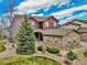 Charming two-story home featuring stone accents, a landscaped yard, and a cozy front porch with mature evergreens at 7999 S Blackstone Pkwy, Aurora, CO 80016