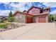 Inviting two-story home featuring stone accents, red siding, a spacious driveway and attached two-car garage at 7999 S Blackstone Pkwy, Aurora, CO 80016