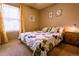 Cozy bedroom featuring a window with yellow curtains, decorative wall art, and a bed with a floral comforter at 10735 W Dartmouth Ave, Lakewood, CO 80227