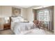 Bright bedroom featuring a bed with decorative throw, window with curtains, chair, and accent table at 185 Players Club Dr, Castle Rock, CO 80104