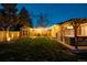 Night view of backyard with hot tub, shed, patio, string lights, cornhole game, and manicured lawn at 7039 Otis Ct, Arvada, CO 80003