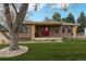 Charming single-story home featuring a red front door, well-manicured lawn, and mature shade trees at 7039 Otis Ct, Arvada, CO 80003
