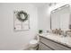 A half bathroom with a gray vanity, white marble countertop, and decorative wreath at 2226 Weatherstone Cir, Highlands Ranch, CO 80126