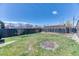 Large backyard with a grassy area, a tall wooden fence, and mature trees for a peaceful retreat at 7621 Granada Rd, Denver, CO 80221