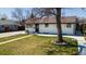 Delightful single-story house with a lush green lawn, mature tree, and a classic white brick facade at 7621 Granada Rd, Denver, CO 80221