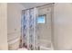 White tiled shower-tub combo with a patterned shower curtain at 7621 Granada Rd, Denver, CO 80221