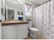 Bathroom features sink vanity, toilet, and shower with patterned curtain at 3230 S Decatur St, Denver, CO 80236