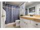 Bathroom features sink vanity, toilet, and shower with blue patterned curtain at 3230 S Decatur St, Denver, CO 80236