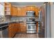 Well-lit kitchen with stainless steel appliances, wooden cabinets, and dark countertops at 3230 S Decatur St, Denver, CO 80236
