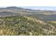 Breathtaking aerial view of a property with a house situated amidst a vast, tree-covered mountain landscape at 26752 Vosler St, Conifer, CO 80433
