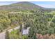Aerial view showcasing a metal-roofed house surrounded by lush greenery and a picturesque mountain backdrop at 26752 Vosler St, Conifer, CO 80433