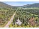 An aerial view of a home with a metal roof on a lush property with trees and mountain views at 26752 Vosler St, Conifer, CO 80433