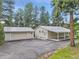 Aerial view of home with asphalt driveway, detached garage, metal roof, and green trees at 26752 Vosler St, Conifer, CO 80433