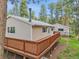 Rear view of the house with light siding and a large wooden deck nestled among the trees at 26752 Vosler St, Conifer, CO 80433
