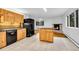 Bright kitchen featuring knotty wood cabinets, center island, black appliances, and stone fireplace at 26752 Vosler St, Conifer, CO 80433