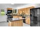 Well-lit kitchen boasts wood cabinets, black appliances and island with granite countertop at 26752 Vosler St, Conifer, CO 80433