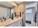 Bright bathroom features a double sink vanity with white cabinets and a large mirror, plus a separate shower and tub at 12881 Park Creek Way, Firestone, CO 80504
