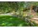 Lush backyard featuring vibrant green grass, mature trees, and a charming stone retaining wall at 7030 S Fillmore Ct, Centennial, CO 80122