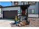 Inviting front porch with a red door, lush landscaping, and a spacious two-car garage at 6454 Leathers Ln, Parker, CO 80134