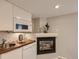 Modern basement kitchen with sleek white cabinetry, a built-in microwave, and a cozy fireplace at 1615 Osceola St, Denver, CO 80204
