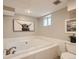 Bright bathroom featuring a large soaking tub with white tile surround and unique artwork on the wall at 1615 Osceola St, Denver, CO 80204