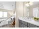 Well-lit bathroom featuring a gray vanity with white countertop, neutral walls, and access to an adjacent bedroom at 1688 S Grant St, Denver, CO 80210