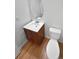 Powder room with wood-look flooring, wood cabinet, and a white toilet and sink at 3932 S Quatar St, Aurora, CO 80018