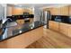 Kitchen featuring wood cabinets, stainless steel appliances, dark countertops, and hardwood floors at 3932 S Quatar St, Aurora, CO 80018