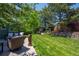 Landscaped backyard showcasing a manicured lawn, mature trees, and stone retaining wall at 1113 Southbury Pl, Highlands Ranch, CO 80129