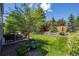 Lush backyard with stone retaining wall, mature trees, and inviting patio area perfect for outdoor enjoyment at 1113 Southbury Pl, Highlands Ranch, CO 80129