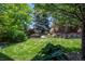 Relaxing backyard with mature trees, landscaping, a bench, and a grassy lawn at 1113 Southbury Pl, Highlands Ranch, CO 80129
