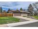 Exterior view of cozy home with a lush green lawn, driveway, and a charming picket fence at 7245 W 70Th Ave, Arvada, CO 80003