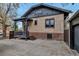 View of brick home with updated windows, covered patio, attached garage, and concrete driveway at 1399 Newton St, Denver, CO 80204