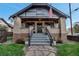 Charming brick home with a welcoming front porch, decorative planters, and an American flag at 1399 Newton St, Denver, CO 80204