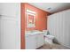 The bathroom features an orange accent wall, ample storage, and a shower with a white curtain at 8435 Pebble Creek Way # 104, Highlands Ranch, CO 80126