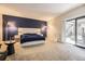 A large main bedroom featuring carpet floors, a navy accent wall, and a sliding door to the patio to expand the space at 4250 S Olive St # 102, Denver, CO 80237