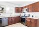 Well-lit kitchen with cherry wood cabinets, updated appliances, and neutral countertops at 8651 Franklin St, Denver, CO 80229