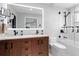 Well-lit bathroom featuring dual sinks, wood vanity, modern fixtures, and tiled shower/tub at 5859 E Ida Pl, Greenwood Village, CO 80111