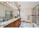 A well lit bathroom with a double sink vanity with granite countertops, a large mirror, and a glass-enclosed shower at 8229 Red Rock Pl, Larkspur, CO 80118