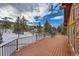 A large wooden deck showing a snowy view of the property and surrounding pine trees at 8229 Red Rock Pl, Larkspur, CO 80118