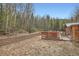 Exterior view of the home and backyard with a hot tub and wooded area at 1645 Little Bear Creek Rd, Idaho Springs, CO 80452