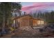 Rustic log cabin exterior with wooden steps and forested backdrop beneath a pink sunset sky at 1645 Little Bear Creek Rd, Idaho Springs, CO 80452